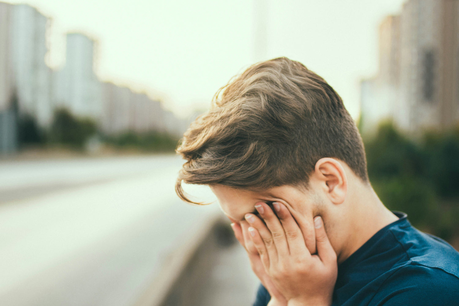 Boy covering his face with his hands because he's tired